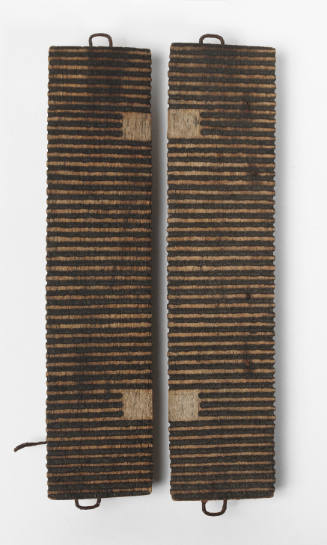Two narrow, vertical wooden boards with shallow, dark-colored parallel grooves carved across