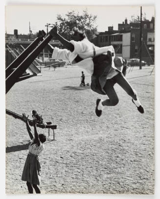 Photo of children with dark skin tone at playground, with one child in foreground swinging in air