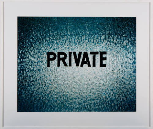 Close-up of a backlit frosted window stenciled with the word “PRIVATE”