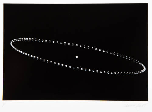 Stop motion photograph capturing an elliptical path of a silver ball centered around a white circle