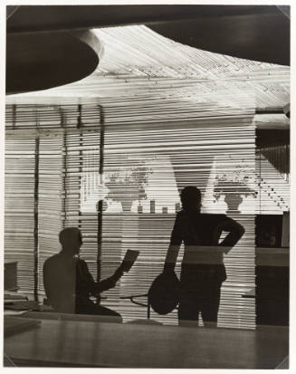 Two figures silhouetted against an office partition composed of horizontal glass rods