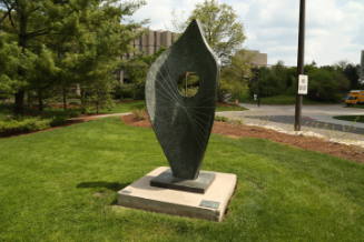 Curved metal sculpture with pointed top and intersecting metal strings attached to each side