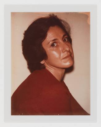 Polaroid of a light-skinned woman in a red sweater looking over her shoulder at the camera