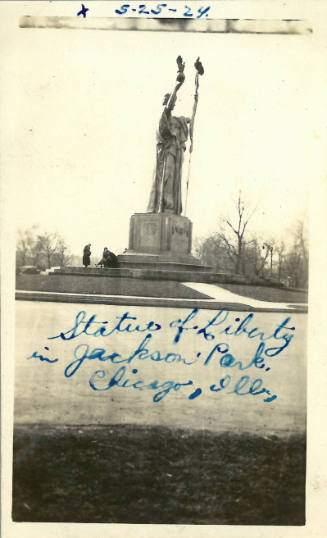 Statue of the Republic on a pedestal in a park during the winter with two people at the base of the 