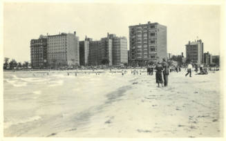Beach city scape, shore and clothed figures in foreground, bathers and and buildings in background