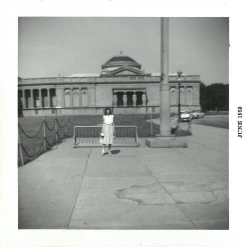 Person in skirt and top stands by bicycle rack, Chicago’s Museum of Science and Industry in backgrou