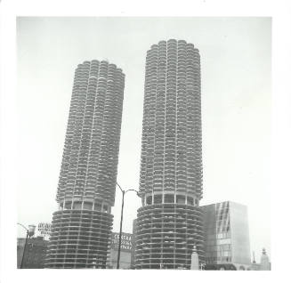 Black-and-white photograph of the two cylindrical Marina City towers rising above Chicago cityscape