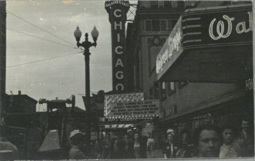 Black-and-white photo of bustling street with streetlamp, lighted vertical marquee reads "CHICAGO"