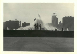 Black-and-white photo of distant view of three people in front of Buckingham Fountain in Chicago