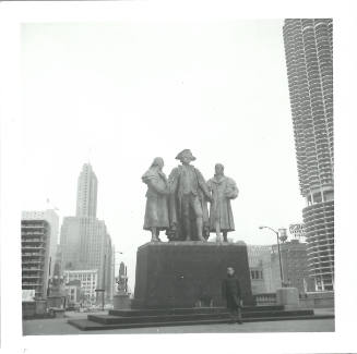 Black-and-white photo of person posing with Heald Square Monument in downtown Chicago