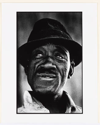 Black-and-white photo portrait of a Black man in a hat looking off into the distance