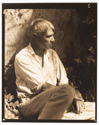 Carl Sandburg, a light-skinned man wearing a button-up, sitting outside, and looking to right