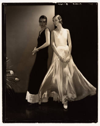 Black-and-white photo of two women in evening wear, one in black dress and the other in white