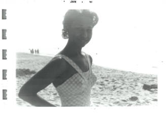 Black-and-white photo of woman with dark skin tone wearing a bathing suit and smiling into camera