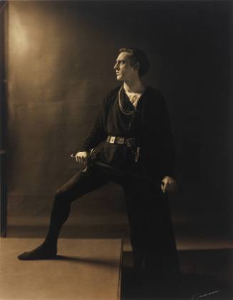 Full-length portrait of John Barrymore facing left wearing stage costume holding a sword