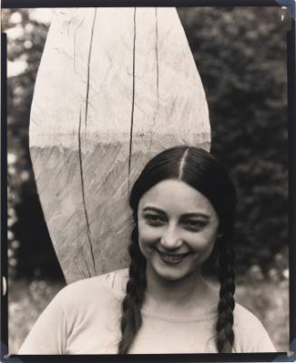 Rosa Covarrubias smiling and wearing two braids stands in front of a sculpture in a garden