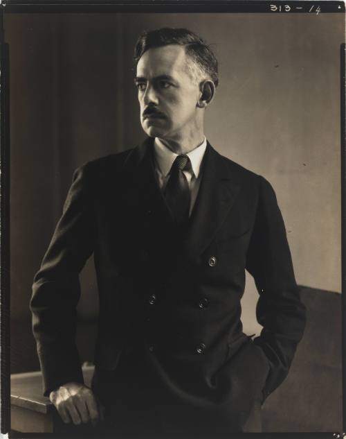 Portrait of Eugene O’Neill, man with light skin tone and dark hair, wearing suit with hand in pocket