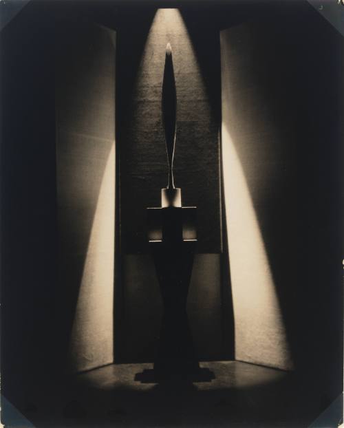 Dramatically lit black-and-white photo of Brancusi’s sculpture Bird in Space before dark backdrop