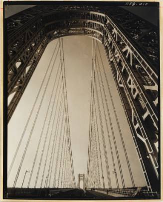 Photo taken from the center of a large bridge, below an arch, with view of cable supports
