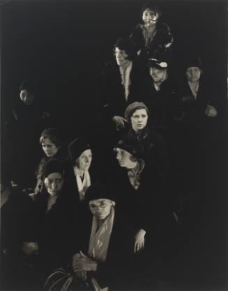Photograph with group of women in coats, scarves, and hats against a dark barkground