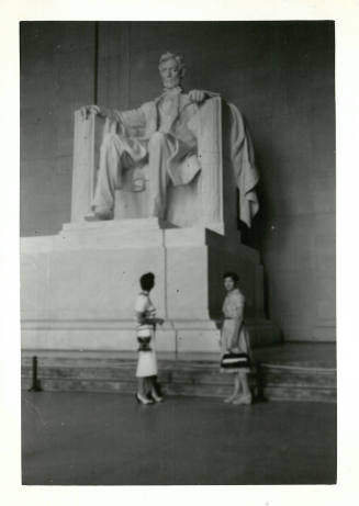 Two women in dresses standing in front of the statue of Lincoln in the Lincoln Memorial