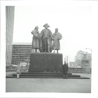 Photo of urban statue with three historic figures and two children in coats posing on either side