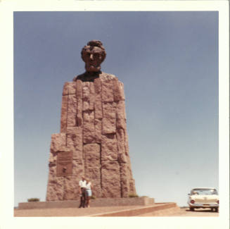 Color photograph of a couple standing in front of a monument with Abraham Lincoln’s head at top 