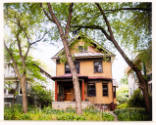 Three-story single-family house with a front yard and garden flanked by similar houses