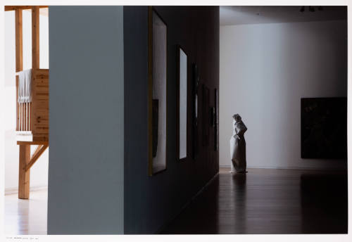Photograph of light streaming into a darkened gallery with a sculpture wrapped with paper 