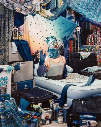 Photograph of man with face painted blue in a room with elaborate collection of blue everyday items