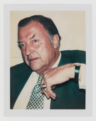 Polaroid portrait of man with graying hair and medium-light skin tone wearing a ring, suit, and tie
