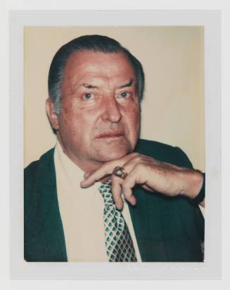 Polaroid portrait of man with graying hair and medium-light skin tone wearing a ring, suit, and tie