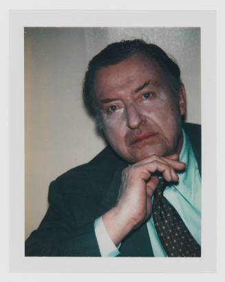 Polaroid portrait of white man with graying hair and cakey makeup on cheekbones, in a suit and tie