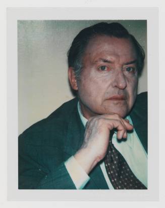 Polaroid of man with graying hair and medium-light skin tone with cakey make-up in suit and tie