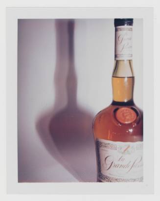 Polaroid of alcohol bottle labeled “Grande Passion” on white background, casting shadow to the left