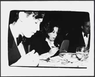 Black-and-white photo of three people in black tie dress eating at round table