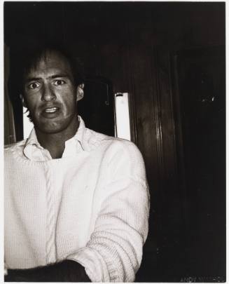 Black-and-white photo of man wearing white sweater looking into camera with surprised expression