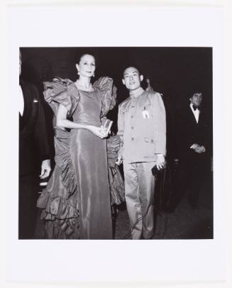 The artist wears a Zhongshan suit and stands next to a woman wearing a dress with huge ruffles