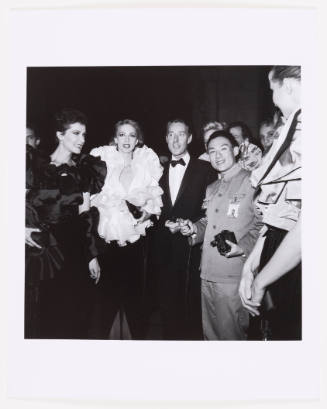 Black-and-white photo of large crowd of adults in formal dress posing with man in Mao suit