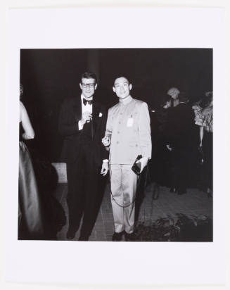 Black-and-white photo of man with glasses in tuxedo posing with man in Mao suit