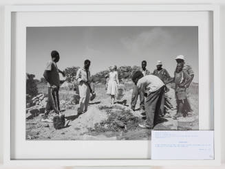 Black-and-white photo of a group of eight people outside working on mixing mortar