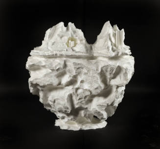Sculpture of white miniature landscape of city and mountains emerging from a subterranean landform