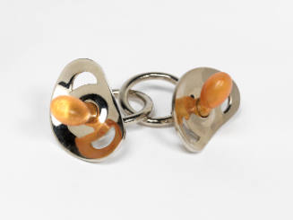 Two matching metal infant pacifiers interlocked by the holding rings