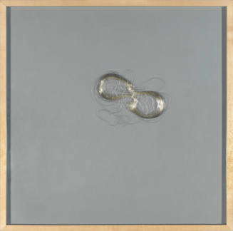 Coiled thin silver wire in a figure-8 shape on grey paper backing with light wooden frame