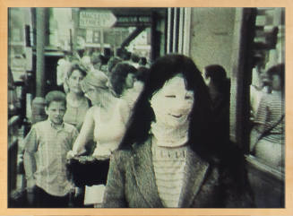 Black-and-white image of woman with long dark hair on busy street with face and neck covered by cast