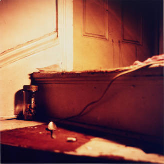 Close-up color photograph of dirty wooden staircase with a spoon, a cord, and a small jar