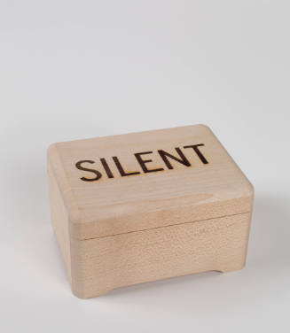 Plain wooden rectangular box, the word silent spelled in all caps burned into the surface of the lid
