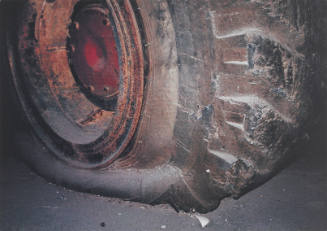 Full-frame image of large worn industrial wheel rim and deflated tire lit with camera flash