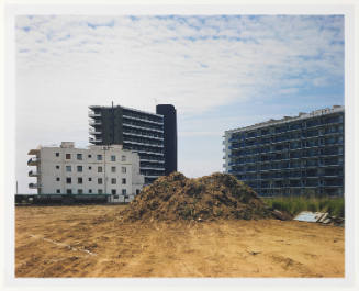 Three multi-storied buildings foregrounded with earth that has been scraped and piled into mound