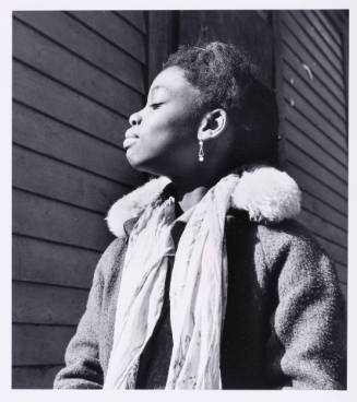 Profile view of a Black girl basking in the sun, her dainty earring in the center of photograph